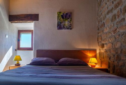 une chambre avec un lit avec deux oreillers et deux lampes dans l'établissement Le four, ferme de la beyssiere, à Saint-Jean-Chazorne