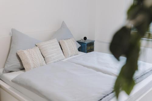 ein weißes Bett mit Kissen und einem Nachttisch in der Unterkunft Stilvoll&Modern-Nähe DUS und CGN in Wuppertal
