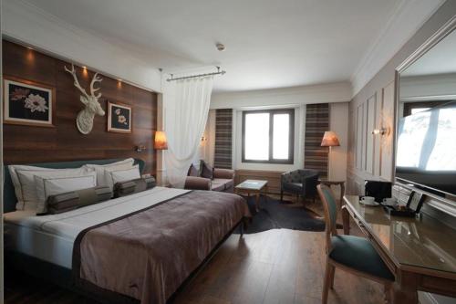 a hotel room with a large bed and a desk at Kaya Palazzo Ski & Mountain Resort in Kartalkaya