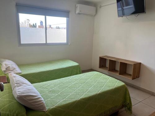 a room with two green beds and a window at HueneyRuca in Mina Clavero