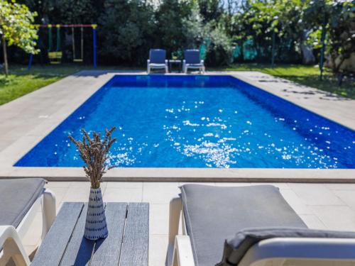 a swimming pool with chairs and a vase on a table at Holiday Home Villa Toni by Interhome in Umag