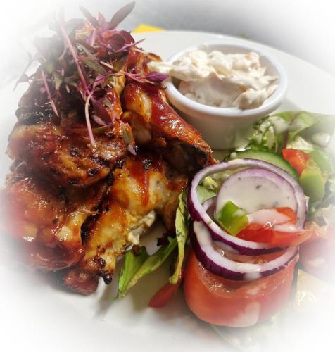a plate of food with chicken wings and a salad at The Red Lyon Slinfold in Slinfold