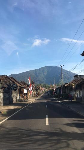 an empty road in a town with mountains in the background at Carik Tangis Boutique Homestay in Jatiluwih