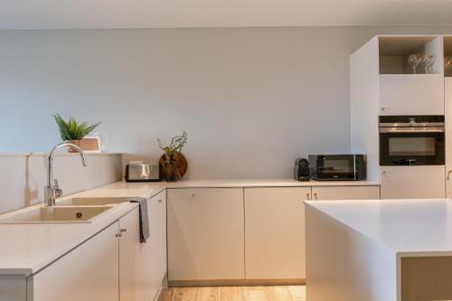 Una cocina con gabinetes blancos y un fregadero. en Huswell - House Tilo: A blend of heritage, scenery, and comfort for 8 Guests, en Ypres