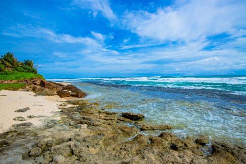 a beach with rocks and the ocean on a cloudy day at Nibbana Mirissa Hotel in Mirissa
