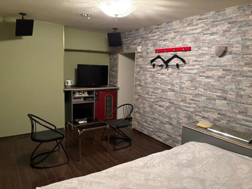 a bedroom with a brick wall with a bed and chairs at City Hotel Dolphin in Tokyo