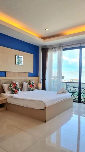 a bedroom with a large bed with blue walls and windows at Samed Port View in Ko Samed