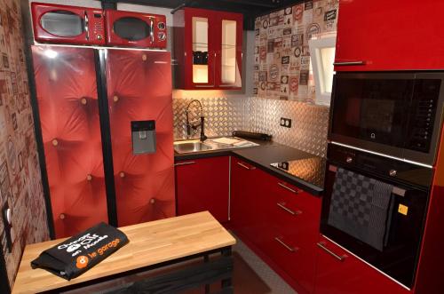 une cuisine avec des placards rouges, un four micro-ondes et une table dans l'établissement Le Garage - Changer d'air en Moselle, à Longeville-lès-Saint-Avold