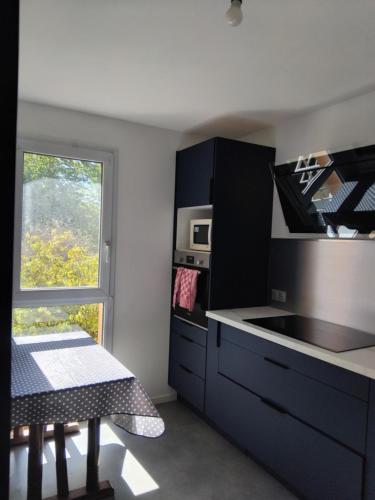 une cuisine avec des placards noirs, une table et une fenêtre dans l'établissement Appartement bien situé, à Rennes