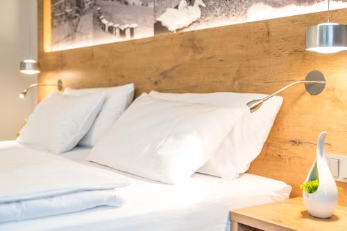 a bed with white pillows and a lamp on a table at Hotel Restaurant Sonne in Gengenbach