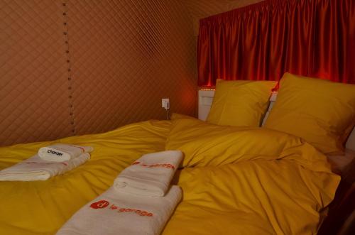 - un lit jaune avec des serviettes dans l'établissement Le Garage - Changer d'air en Moselle, à Longeville-lès-Saint-Avold