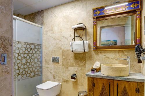 a bathroom with a toilet and a sink and a mirror at Kasr-ı Kapadokya Cave Suites in Ortahisar