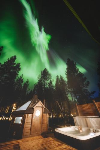a cabin under the northern lights at night at Villa ArcticFox Levi in Kittilä