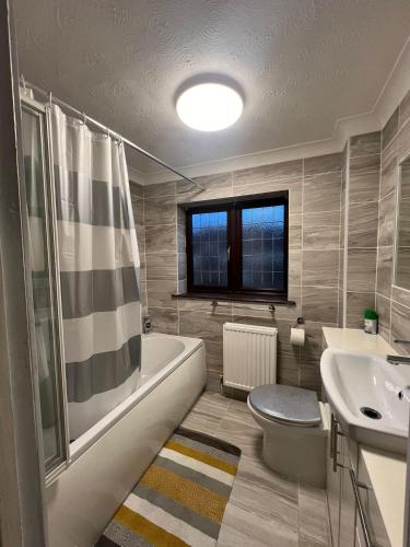 a bathroom with a tub and a toilet and a sink at Charming 3-Bed House - Sleeps 6 Parking & Garden in Grays Thurrock