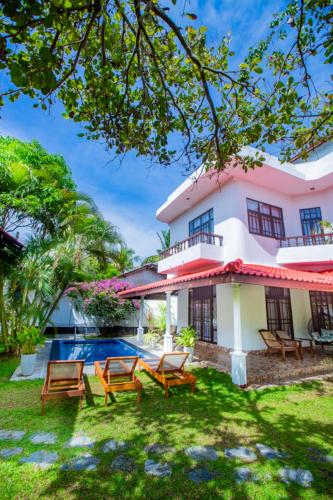 a villa with a swimming pool and a house at Nibbana Mirissa Hotel in Mirissa