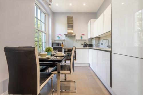 a kitchen with white cabinets and a table and chairs at Maida Vale - Carlton Vale Apartments in London
