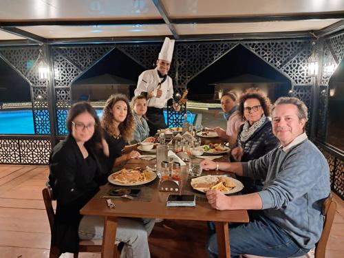 a group of people sitting at a table in a restaurant at Stars Gate Camp in Al Wāşil