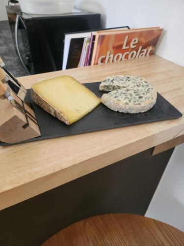 a cutting board with two slices of cheese and a pizza at Chambres hote Le Clos 26 in Bellerive-sur-Allier
