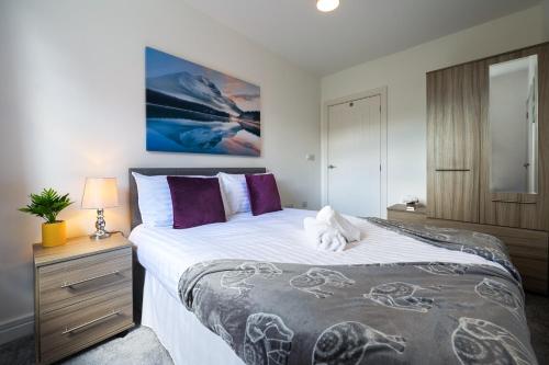 a bedroom with a large bed with purple pillows at Spacious and Bright 2 Bedroom Apartment, Sleeps 6, 1st Floor with Free Parking, Business and Leisure by Jesswood Properties in Hinckley