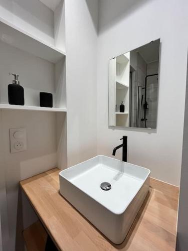 une salle de bain avec un lavabo blanc et un miroir dans l'établissement L'Oasis Vue Mer- MALO LES BAINS, à Dunkerque