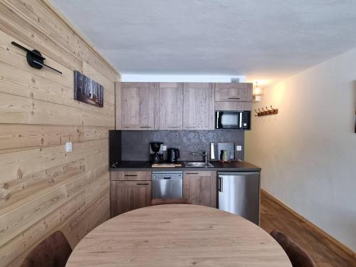 une cuisine avec des armoires en bois et une table en bois dans l'établissement Studio rénové cosy à Plagne Centre avec balcon, skis aux pieds - FR-1-351-176, à La Plagne Tarentaise