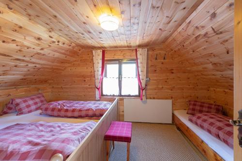 una camera da letto in stile baita di tronchi con 2 letti e una finestra di Idyllische Zirbenholz Alpin Huette a Turracher Hohe