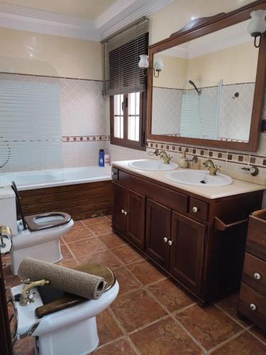 a bathroom with two sinks and a tub and a toilet at villa verónica in Arriate