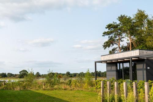 a building in a field with a fence at Hofparken De Bergvennen in Lattrop