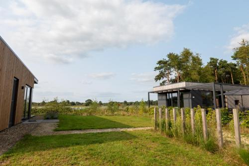 a glass house in a field with a fence at Hofparken De Bergvennen in Lattrop