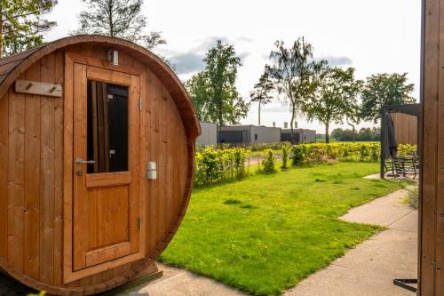 a wooden outhouse with a door in a yard at Hofparken De Bergvennen in Lattrop