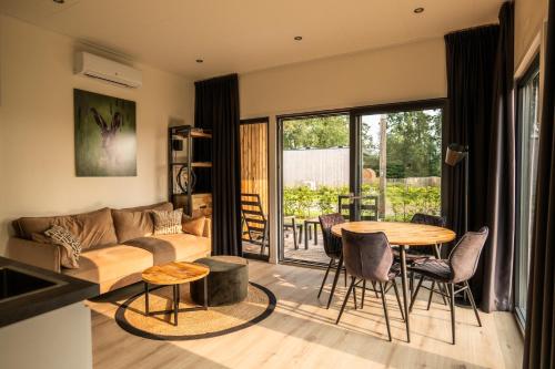 a living room with a couch and a table and chairs at Hofparken De Bergvennen in Lattrop