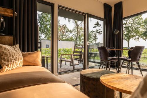 a room with a bed and a balcony with windows at Hofparken De Bergvennen in Lattrop
