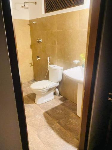 a bathroom with a white toilet and a sink at Lake Duwa Hotel in Ambalangoda