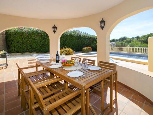 a dining room with a table and chairs and a pool at Villa Oronella by Interhome in Benissa