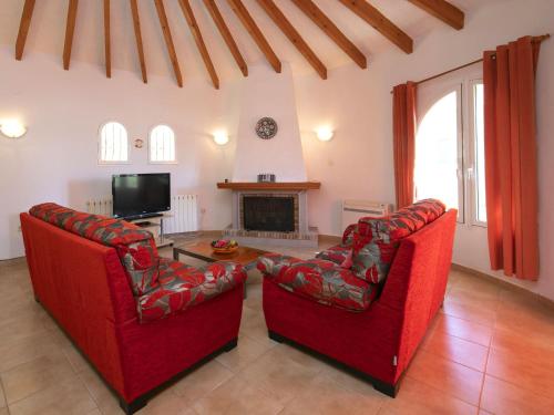 a living room with two red chairs and a tv at Villa Oronella by Interhome in Benissa