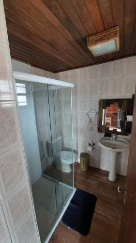 a bathroom with a glass shower and a sink at Pousada Chalés da Felicidade in Itu