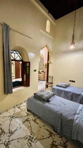 two beds in a room with a window at Riad Dar Al Manzah in Rabat