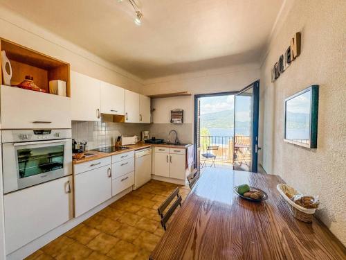 une cuisine avec des armoires blanches, une table et une fenêtre dans l'établissement Joli T3 moderne avec vue imprenable sur la mer, à Propriano