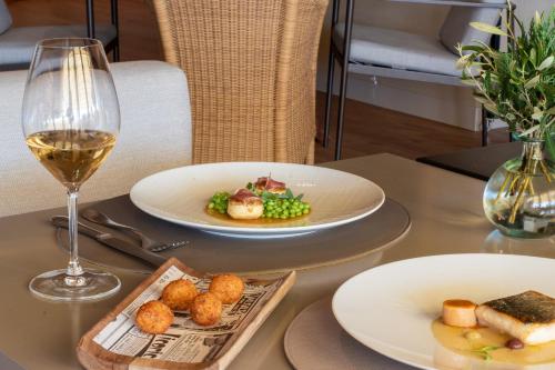 a table with two plates of food and a glass of wine at Hotel Peralada Wine Spa & Golf in Peralada
