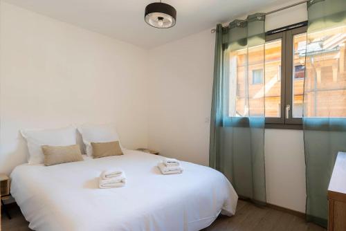 une chambre avec un grand lit blanc et une fenêtre dans l'établissement Apartment Le Nid, aux Gets