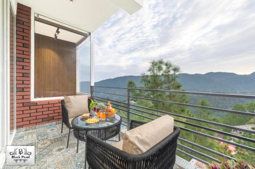 a balcony with two chairs and a table with a view at The BlackPearl Hillcrest in Kasauli