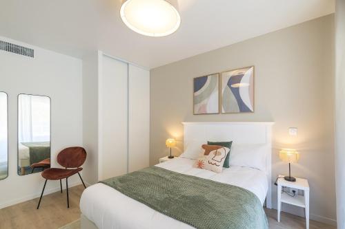 a bedroom with a bed and a chair in it at OVELIA Angers - Les Jardins d'Arborescence in Angers