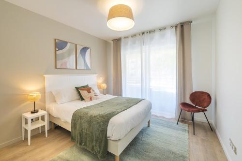 une chambre avec un lit et une grande fenêtre dans l'établissement OVELIA Angers - Les Jardins d'Arborescence, à Angers