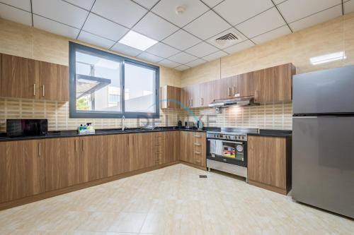 a large kitchen with wooden cabinets and a large window at Best Deal 3BR plus maid's with Pool Perfect for Groups by Deluxe Holiday Homes in Fujairah