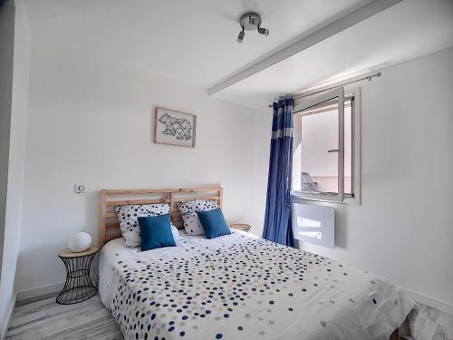 une chambre avec un lit avec des oreillers bleus et une fenêtre dans l'établissement L'ABBAT-JOUR - Le Nelli - Calme - Lumineux, à Tarbes