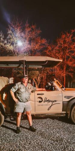 a man standing next to a car with a surfboard on top at Umoya Safari Lodge in Matlhagame