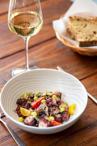 a white bowl of food and a glass of wine at La Ferme Chapouton - Teritoria in Grignan