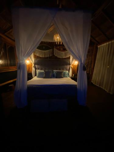 Schlafzimmer mit einem Bett mit blauen Vorhängen in der Unterkunft Evamayah in Leona Vicario