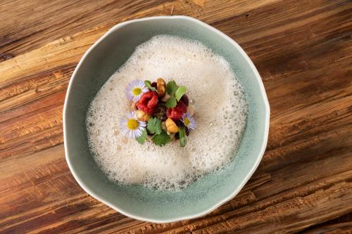 a bowl of rice with berries and flowers on a wooden table at Skyview Chalets am Camping Toblacher See in Dobbiaco