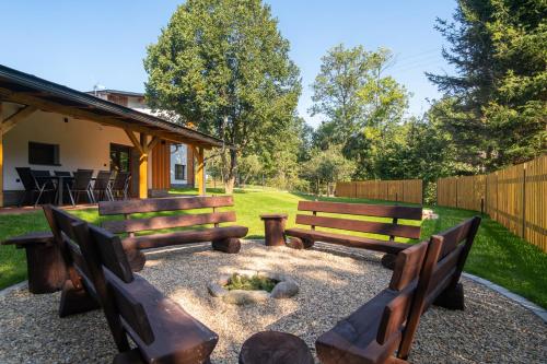 two benches sitting next to a fire pit in a yard at RONI Apartments Krkonoše in Cerny Dul